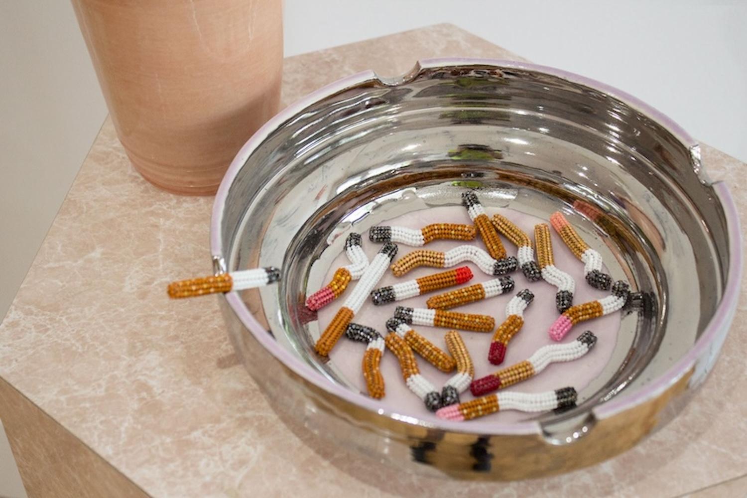 Silver ceramic lustre ashtray full of beaded cigarettes