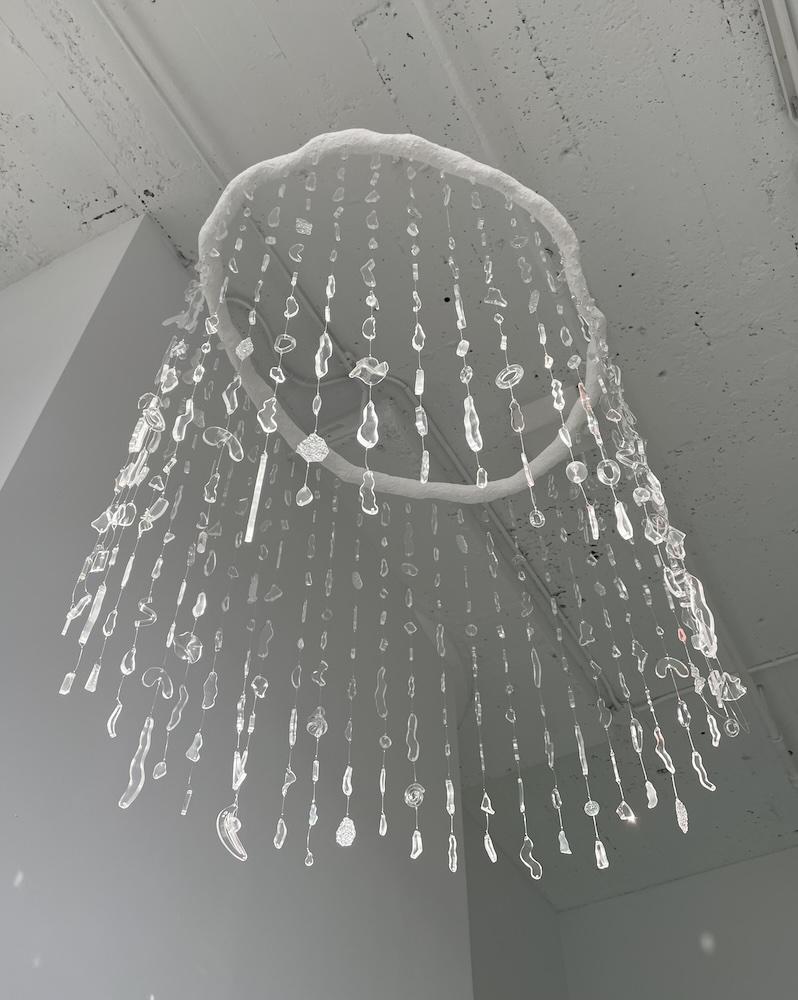 Image of a spinning mobile made of wire, papier mache and dangling lucite sculptures